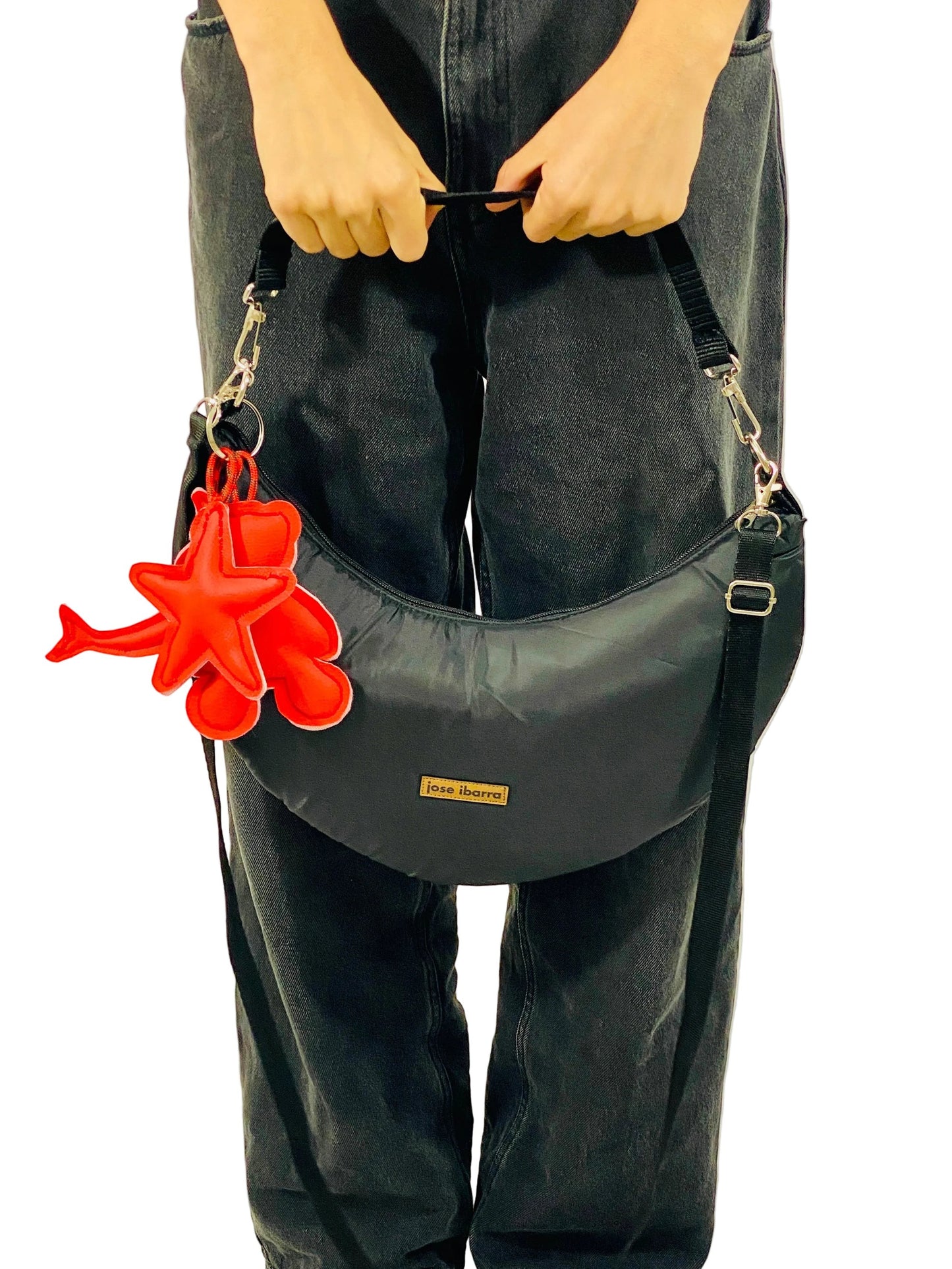 Jose Ibarra black crescent-shaped crossbody bag made of thick cotton with a red star and teddy bear charm. Includes strap.