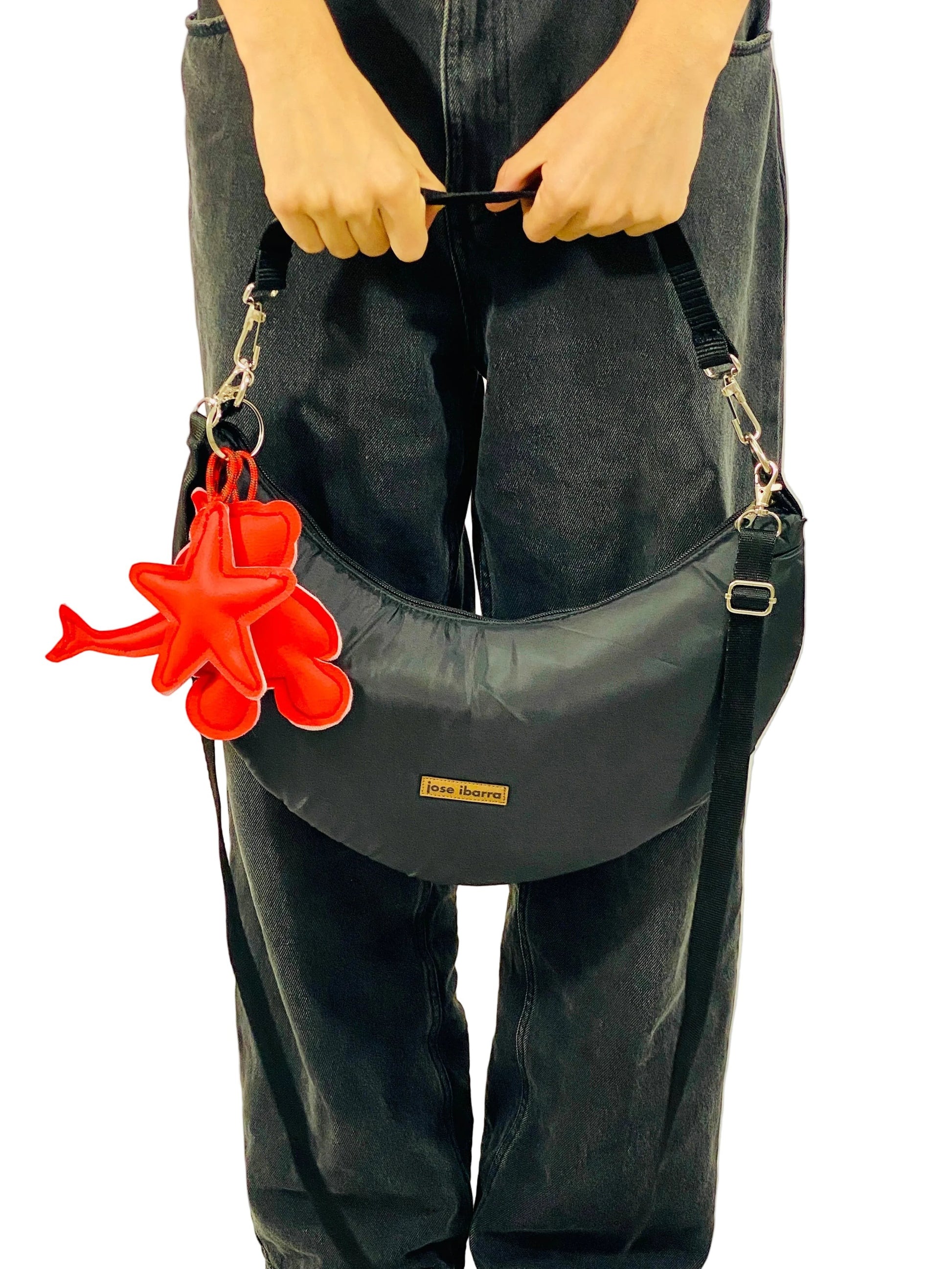 Jose Ibarra black crescent-shaped crossbody bag made of thick cotton with a red star and teddy bear charm. Includes strap.