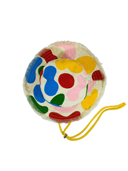 Jose Ibarra Estudio cream cotton bucket hat with colorful abstract hand-painted shapes and frayed brim. Yellow drawstring.