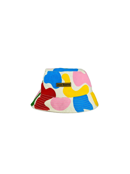 Jose Ibarra Estudio cream cotton bucket hat with abstract hand-painted shapes in blue, pink, yellow, and red.