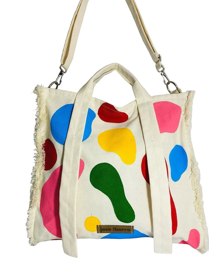 Jose Ibarra Estudio cream canvas tote bag with colorful abstract paint splatters and frayed edges. Includes shoulder strap.