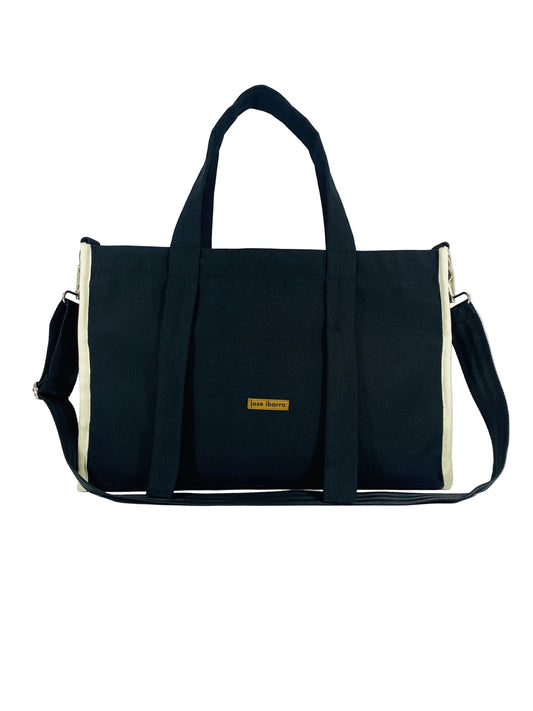 Jose Ibarra Estudio black canvas tote bag with cream trim and adjustable strap. Features internal lining and pockets.