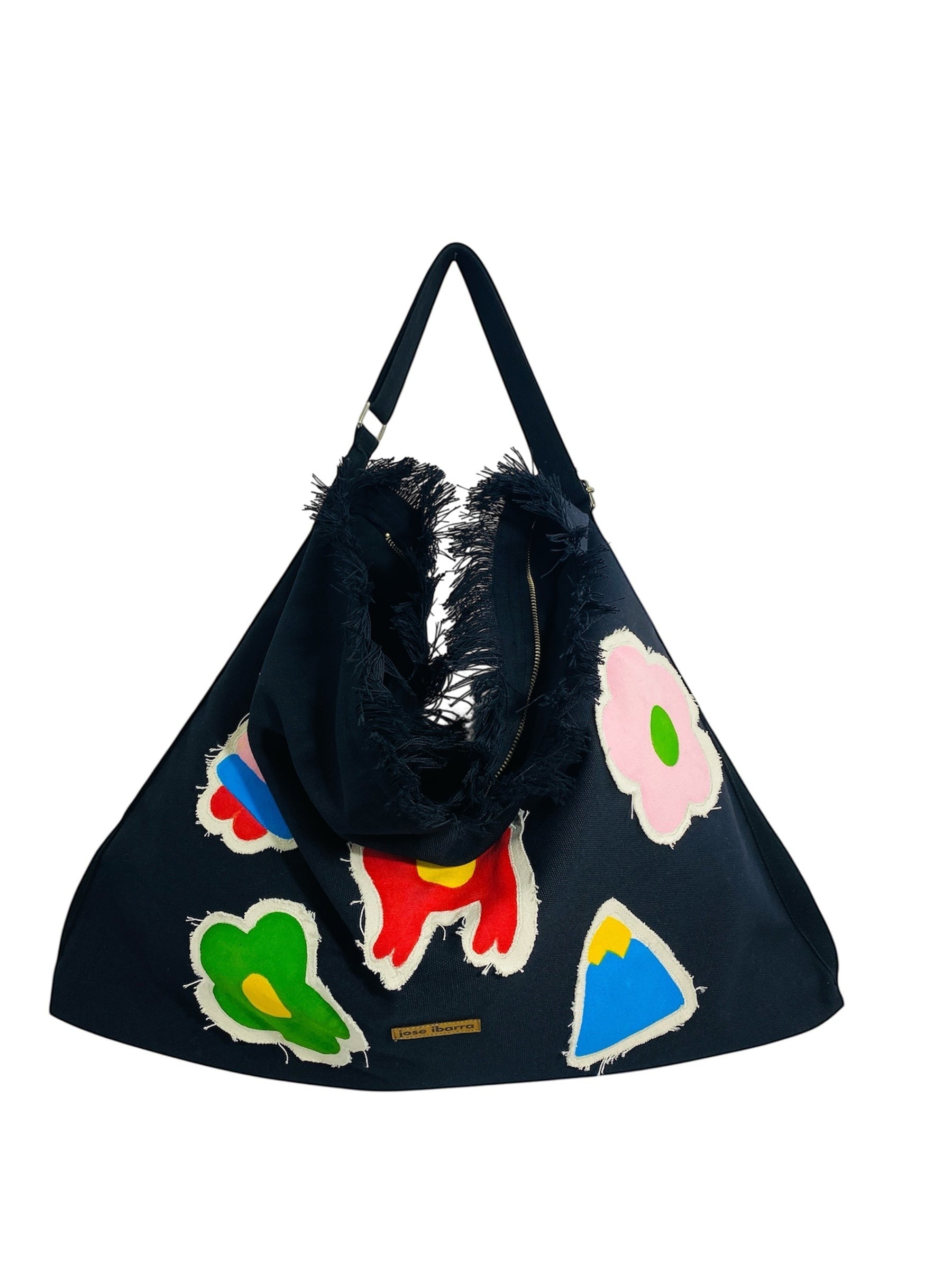 Jose Ibarra Estudio black cotton canvas tote bag with hand-painted colorful appliques and frayed edges.