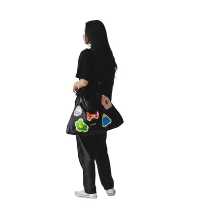 Jose Ibarra Estudio black cotton tote bag with hand-painted colourful patches and frayed edges, adjustable strap.