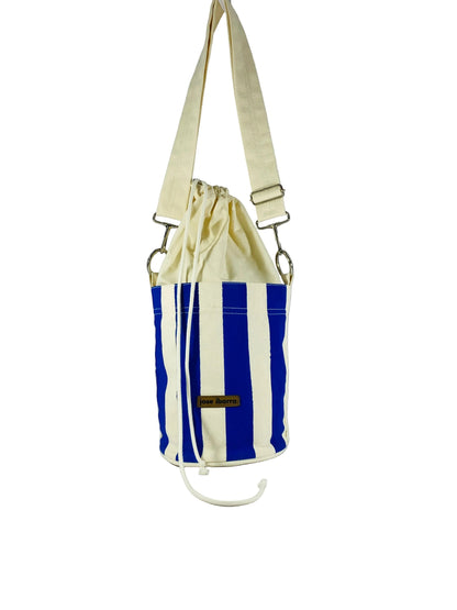 Jose Ibarra Estudio blue and white striped canvas bucket bag with drawstring closure and adjustable strap.
