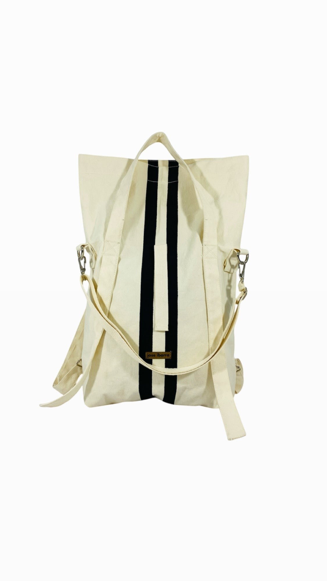 Jose Ibarra Estudio cream canvas tote bag with black vertical stripes, convertible to backpack or crossbody.