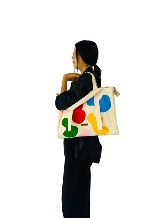 Jose Ibarra Estudio cream canvas tote bag with hand-painted abstract colorful shapes and a strap. Includes internal lining.