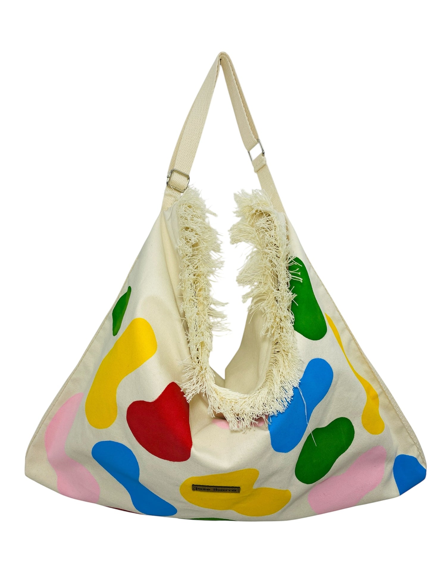 Jose Ibarra Estudio cream cotton canvas tote bag with abstract hand-painted colorful shapes and frayed edges.
