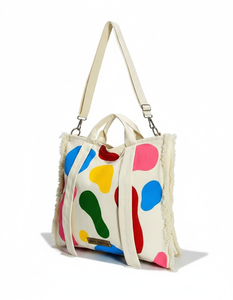 Jose Ibarra Estudio cream canvas tote bag with colorful abstract paint splatters and frayed edges. Includes shoulder strap.