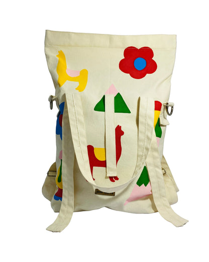 Jose Ibarra Estudio cream cotton canvas tote bag with hand-painted colorful llama, flower, and geometric designs. Convertible to backpack or crossbody.
