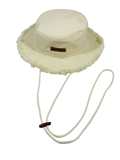 Jose Ibarra Estudio cream canvas bucket hat with frayed brim and adjustable chin strap. Hand-painted details.
