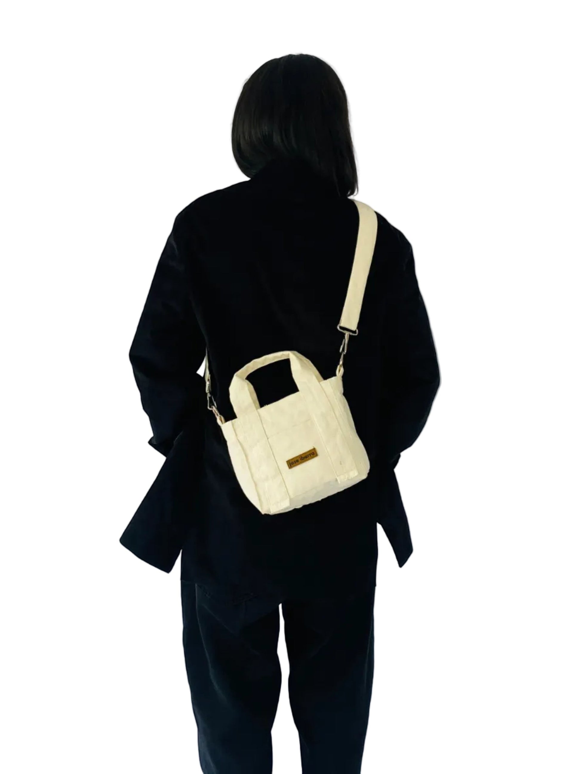 Jose Ibarra Estudio cream quilted cotton canvas mini tote bag with hand-painted art and adjustable strap.