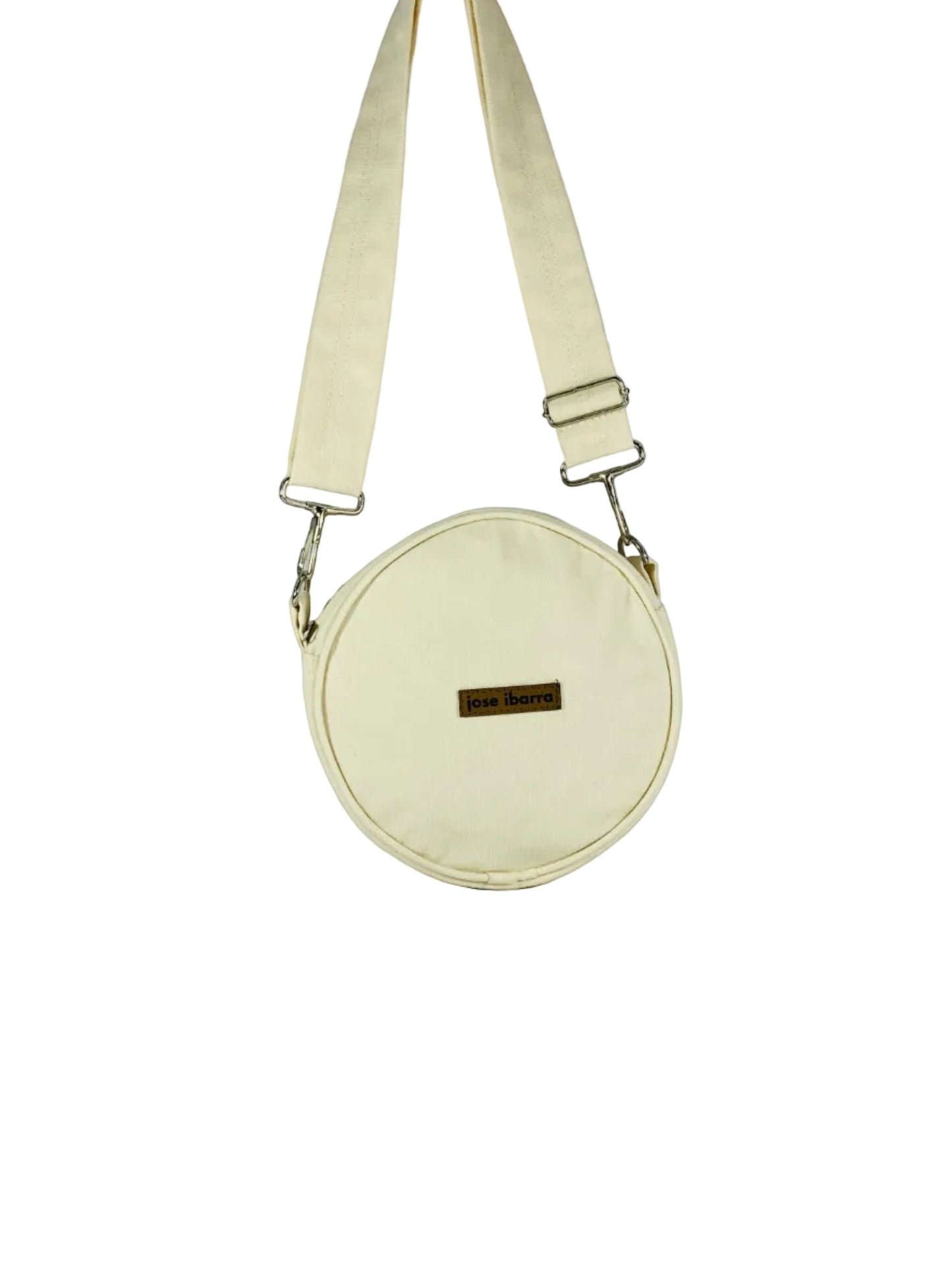 Jose Ibarra Estudio cream canvas round crossbody bag with adjustable strap and leather logo patch.