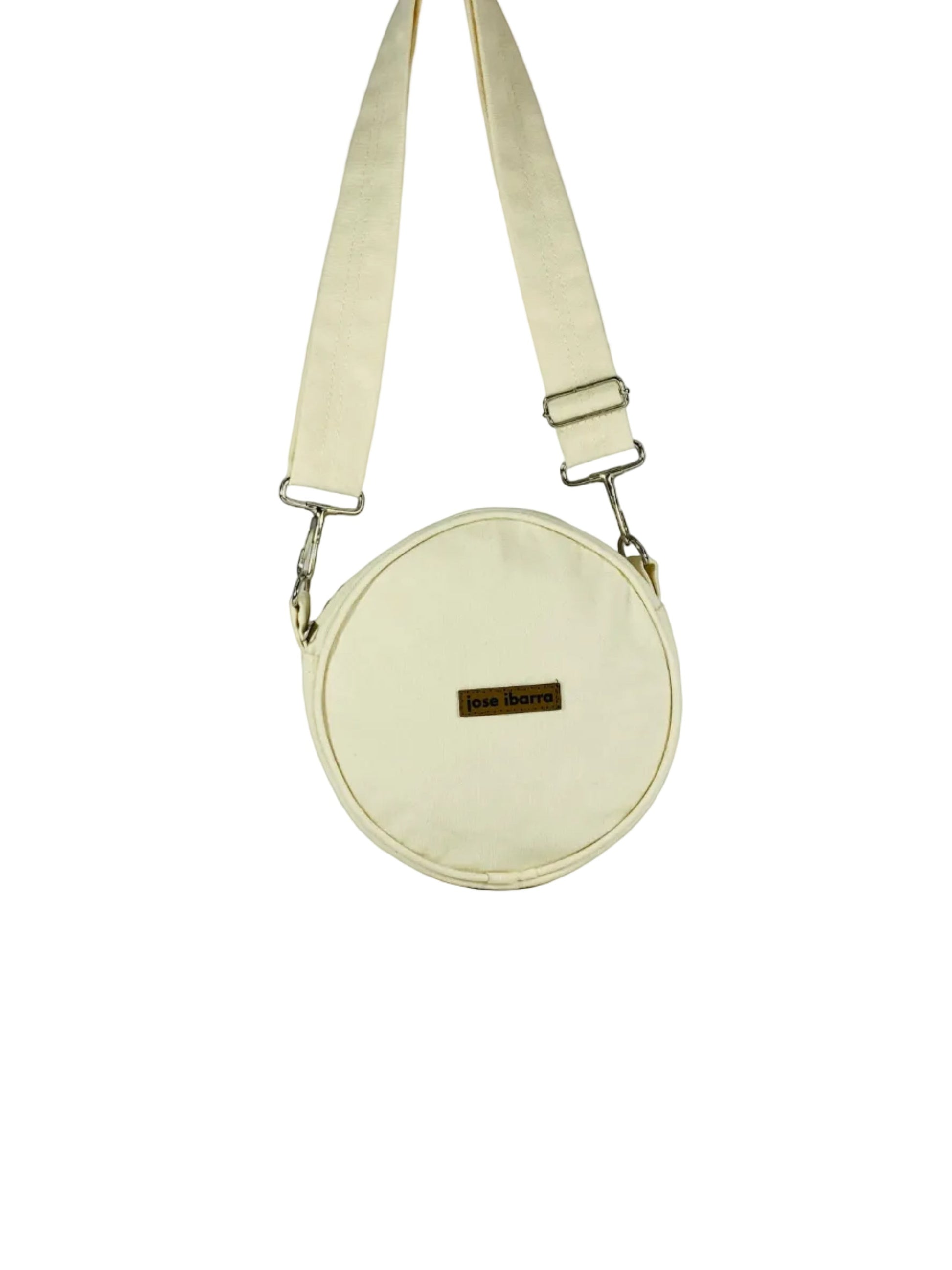 Jose Ibarra Estudio cream canvas round crossbody bag with adjustable strap and leather logo patch.