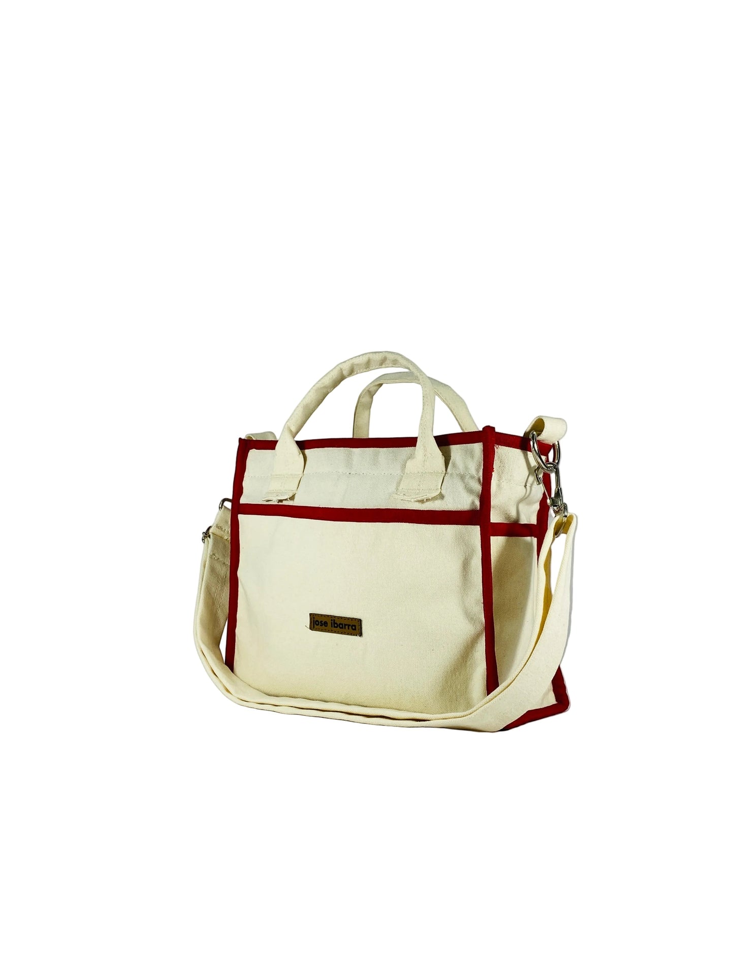 Jose Ibarra Estudio cream canvas tote bag with red trim and adjustable strap. Features internal pockets and a brand tag.