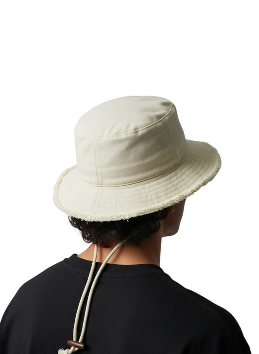 Jose Ibarra Estudio cream cotton bucket hat with frayed brim and adjustable chin strap. Hand-painted details.