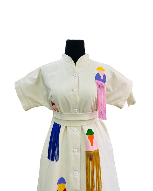 Jose Ibarra Estudio cream cotton dress with hand-painted Andean figures and colorful fringe details.