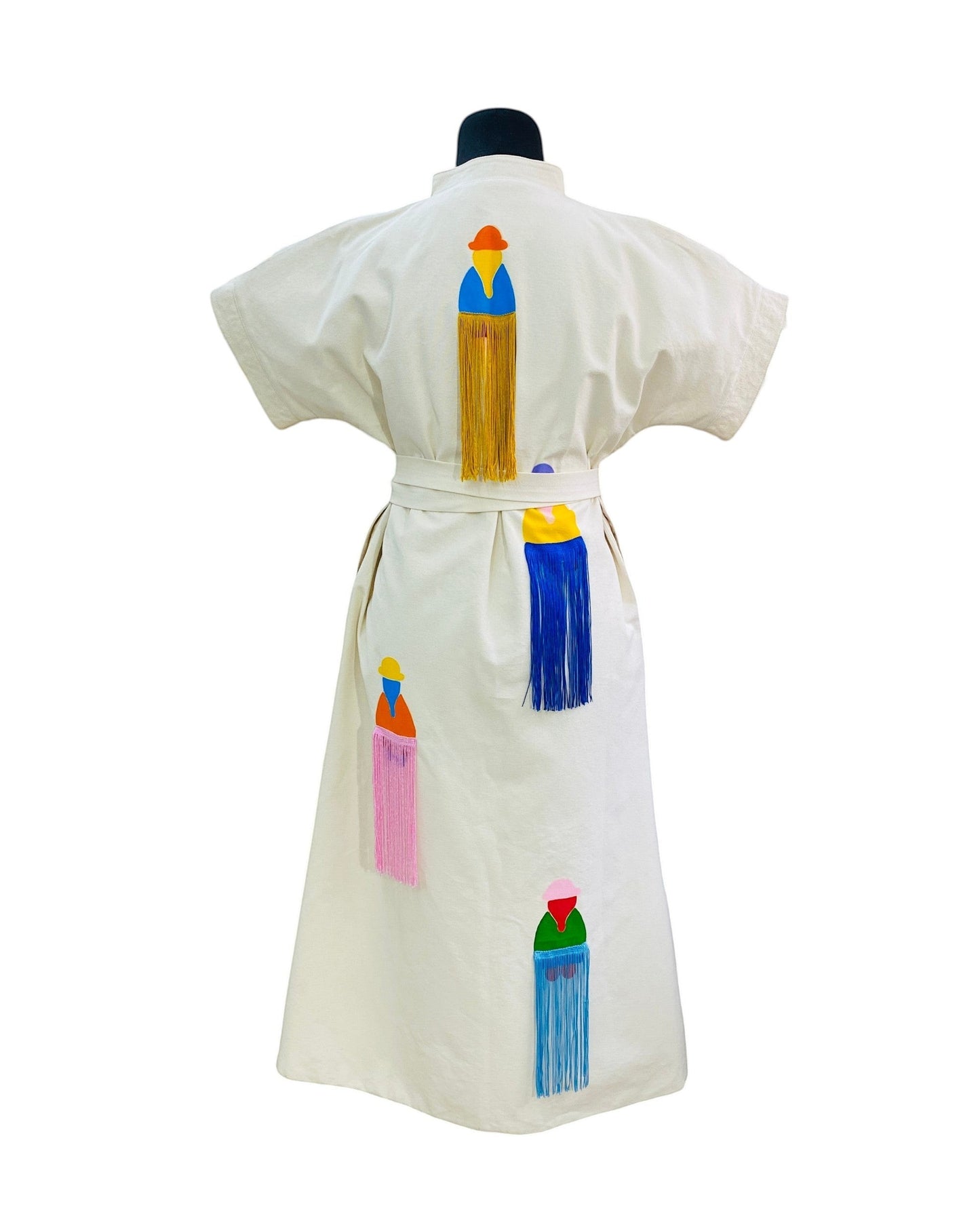 Jose Ibarra Estudio cream cotton dress with hand-painted Andean figures and colorful fringe details. Midi length, short sleeves, belted waist.