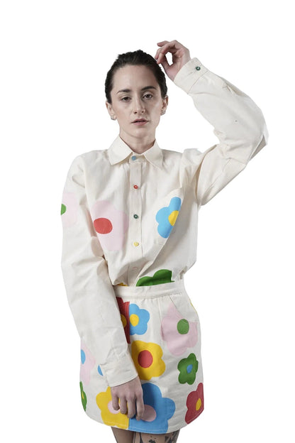 Jose Ibarra Estudio cream 100% cotton loose-fit shirt with hand-painted colourful flowers and contrasting buttons.