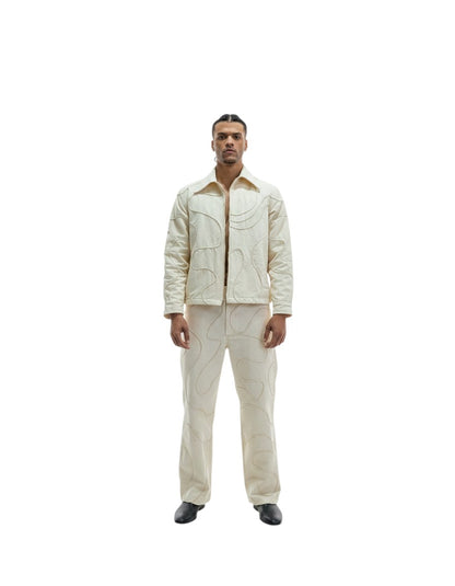 Jose Ibarra Estudio cream cotton jacket and pants set with abstract stitching, worn by a male model.
