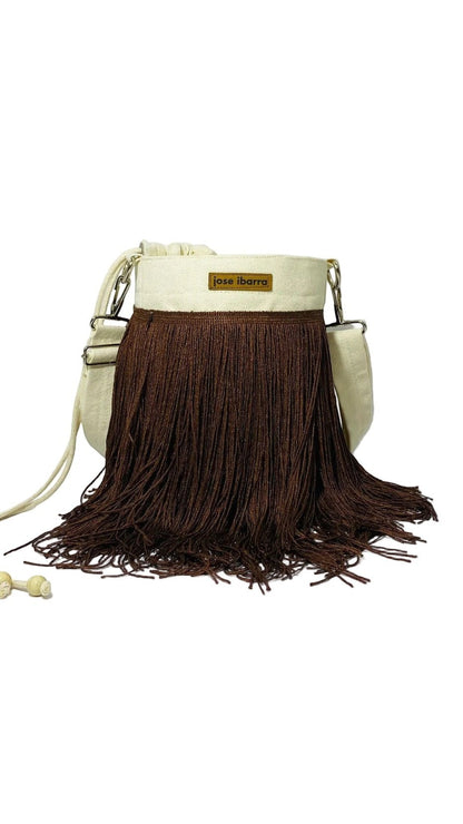 Jose Ibarra Estudio cream canvas bucket bag with long brown fringe detail and leather logo patch.