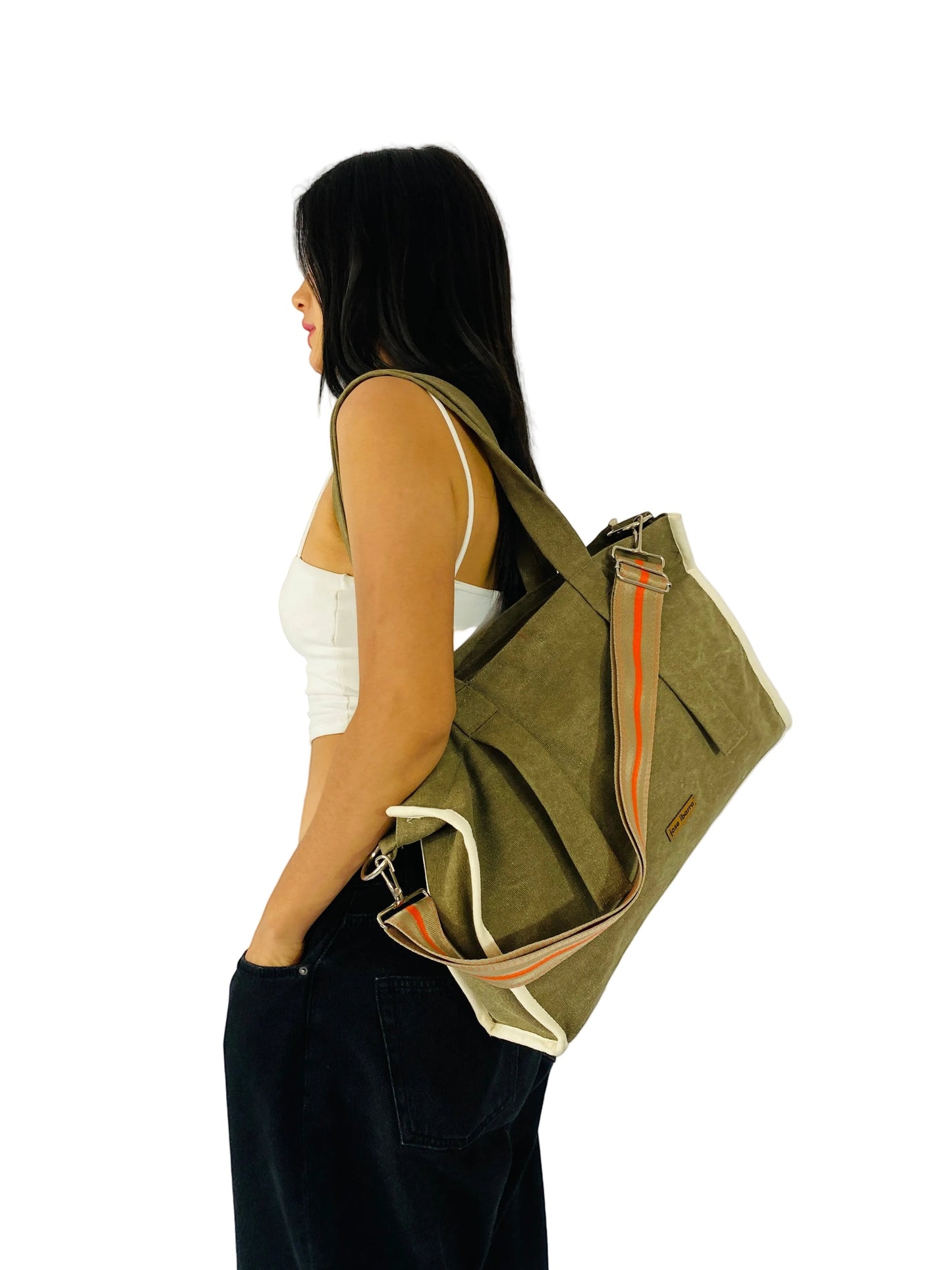 Jose Ibarra Estudio DUA olive green canvas tote bag with orange stripe detail and adjustable strap, worn by a model.