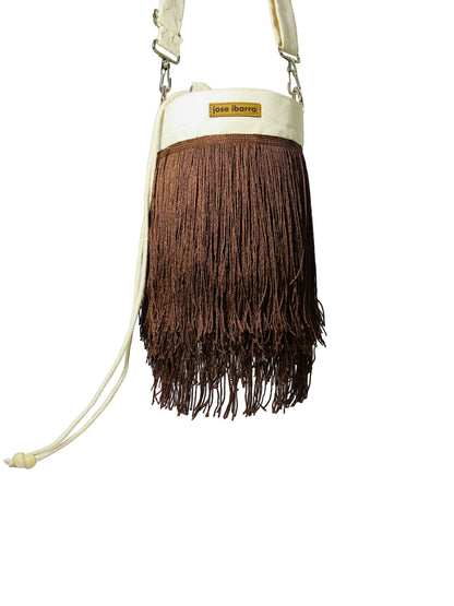 Jose Ibarra Estudio cream canvas bucket bag with brown fringe detailing and adjustable strap.