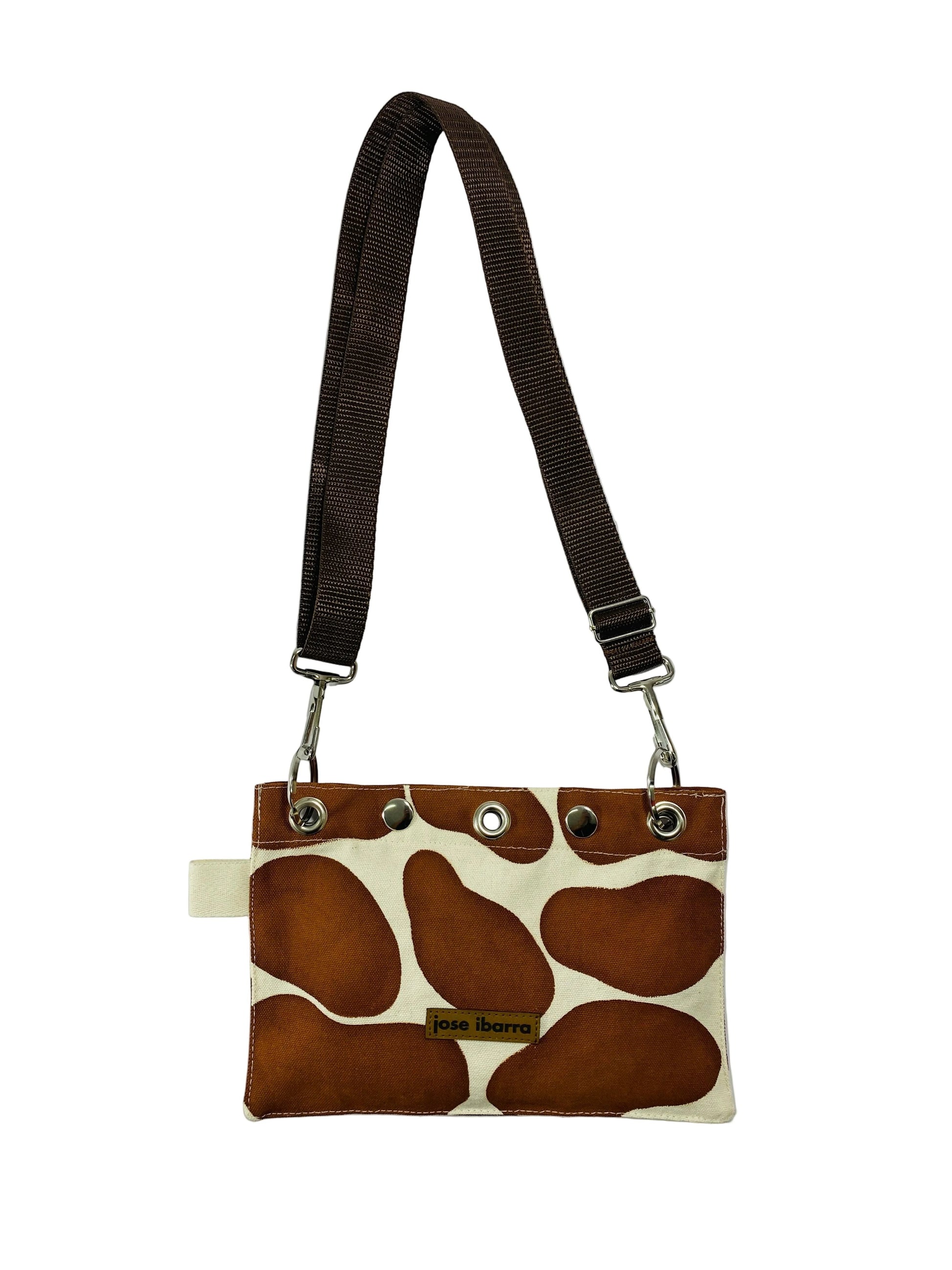 Jose Ibarra Estudio brown and cream giraffe print canvas pouch with adjustable strap and internal lining.