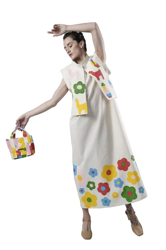 Jose Ibarra Estudio cream 100% cotton canvas vest, hand-painted with colorful animals and flowers, worn over a matching dress.
