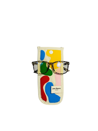 Jose Ibarra Estudio cream cotton glasses case with abstract hand-painted colourful shapes and a white button closure. Includes glasses.