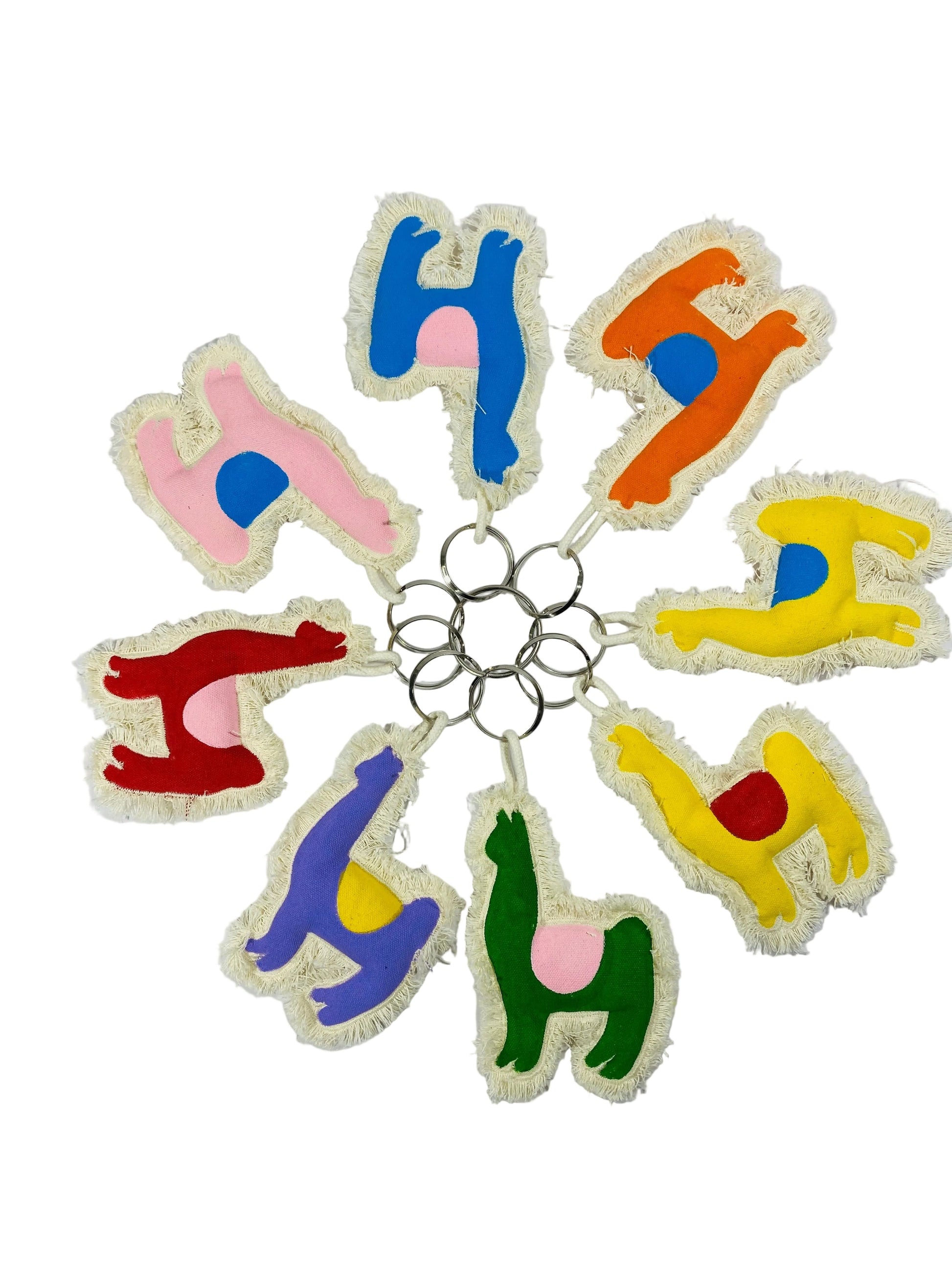 Jose Ibarra Estudio handmade llama keychains in various colors: blue, pink, orange, yellow, red, purple, and green, made of thick cotton canvas with frayed edges.