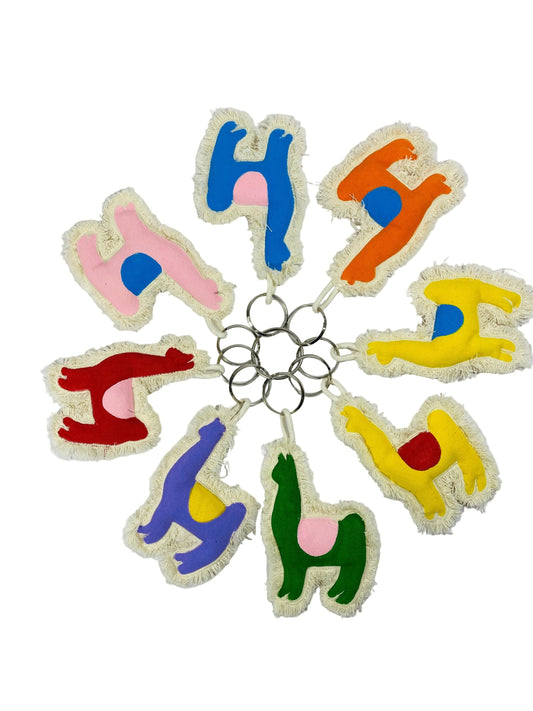 Jose Ibarra Estudio handmade llama keychains in various colors: blue, pink, orange, yellow, red, purple, and green, made of thick cotton canvas with frayed edges.