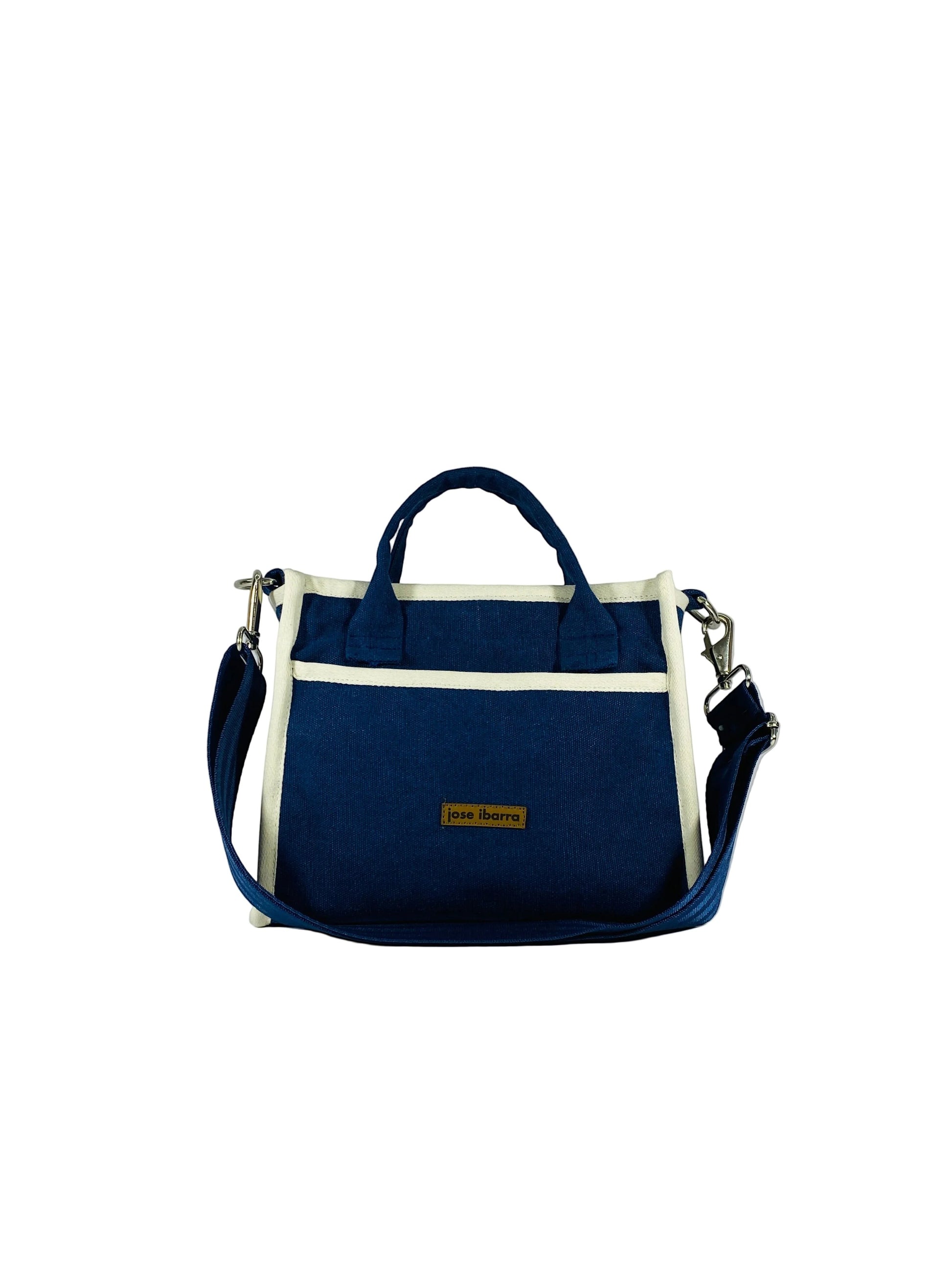 Jose Ibarra Estudio navy blue thick canvas tote bag with cream trim, top handles, and adjustable shoulder strap. Features internal pockets.