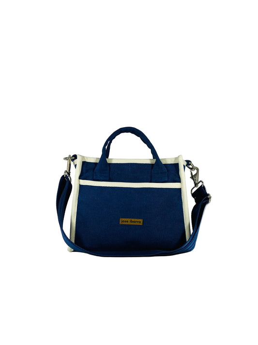Jose Ibarra Estudio navy blue thick canvas tote bag with cream trim, top handles, and adjustable shoulder strap. Features internal pockets.
