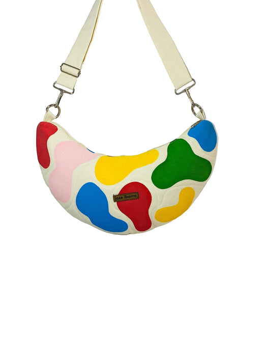 Jose Ibarra Luna crescent crossbody bag in cream cotton with a colourful abstract hand-painted design and adjustable strap.