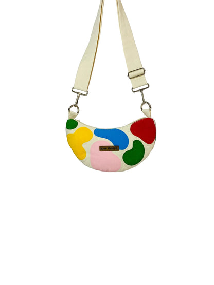 Jose Ibarra Luna cream canvas crossbody bag with colorful abstract appliqué patches and adjustable strap.